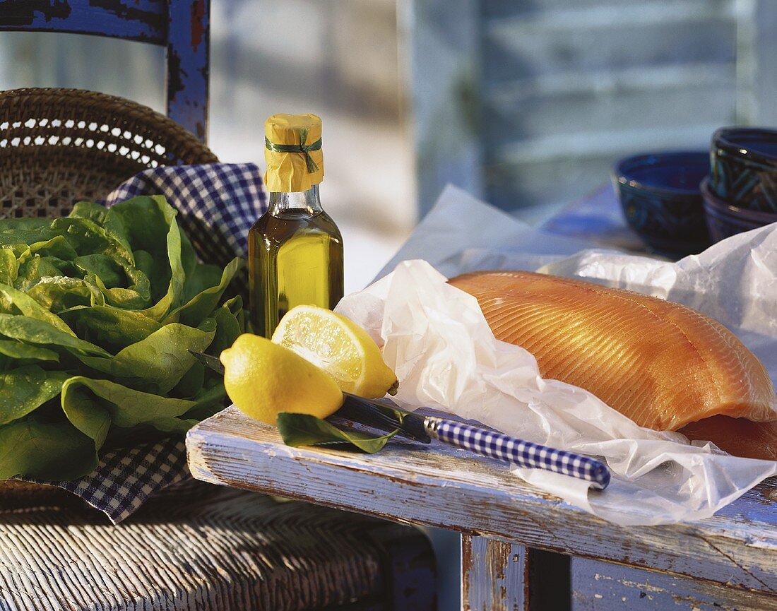 Still life with fresh salmon, lemon, greens and olive oil