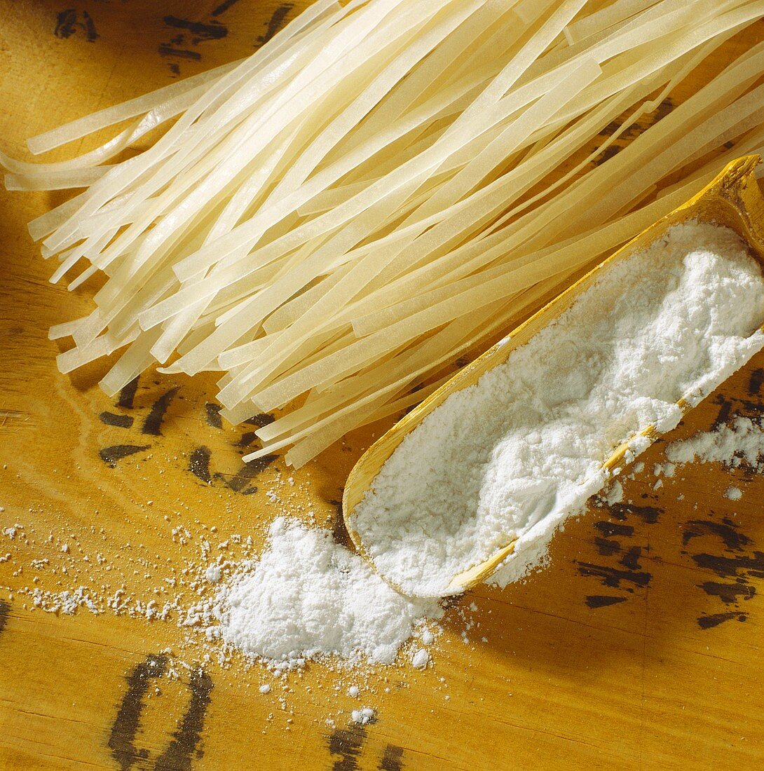 Rice flour on wooden scoop and rice noodles