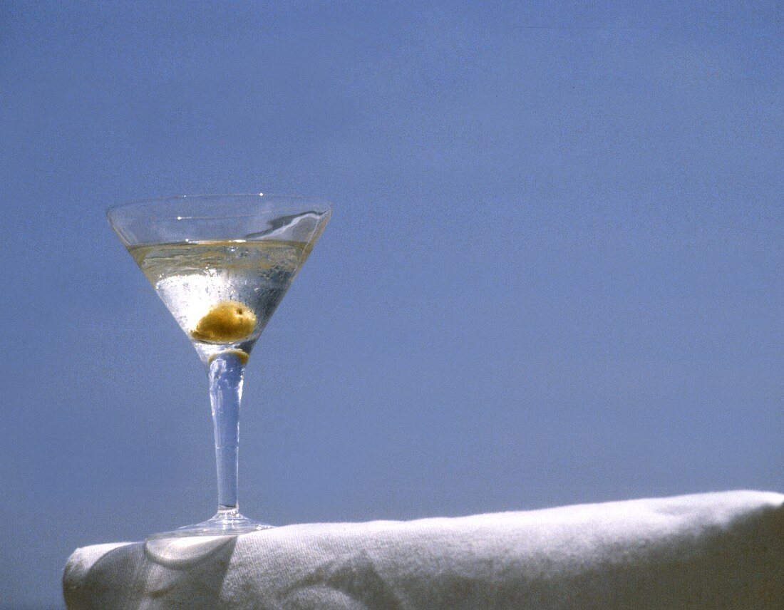Glas Martini auf weisser Stuhlarmlehne vor blauem Himmel