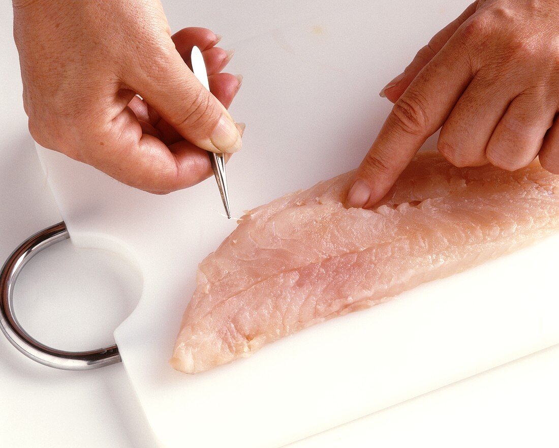 Removing fish bones with tweezers and fingers