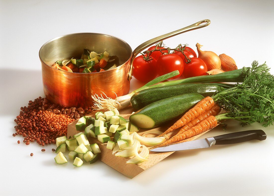 Various vegetables, kitchen knife & pan of diced vegetables