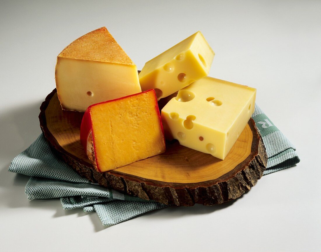 Käse: Appenzeller, Cheddar, Emmentaler auf Holzbrett