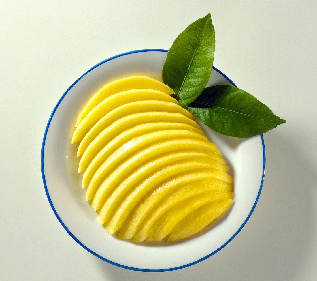 Frische Mango, in Spalten geschnitten, mit zwei Blättern