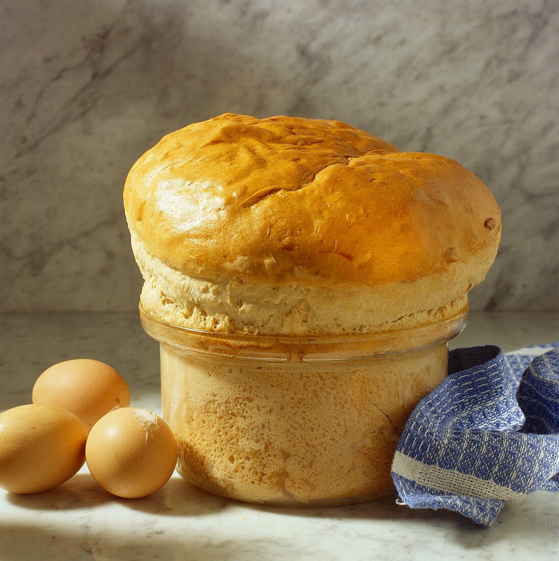 Bread in shape of souffle in souffle dish, a few eggs beside it