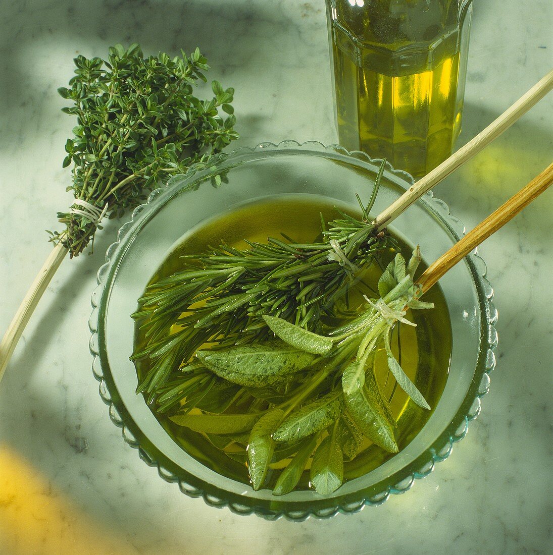 Kräuterpinsel (Salbei, Rosmarin) in Schälchen mit Olivenöl