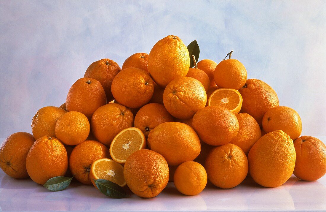 Viele ganze & einige aufgeschnittene Orangen auf einem Haufen