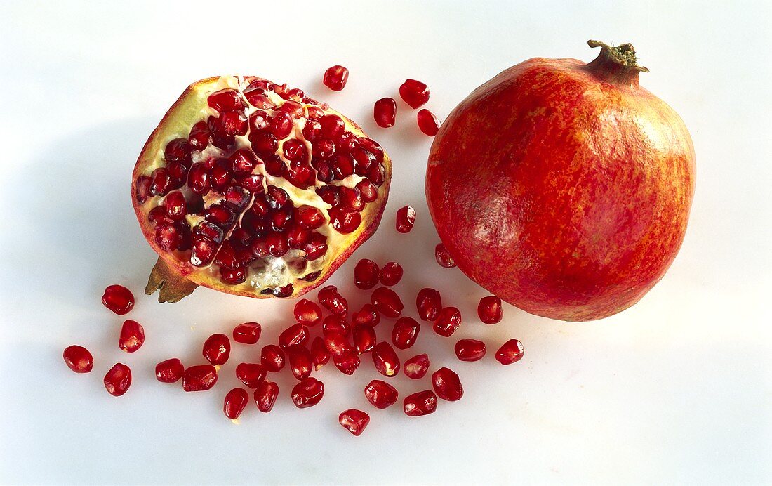 Ganzer & aufgeschnittener Granatapfel mit Kernen