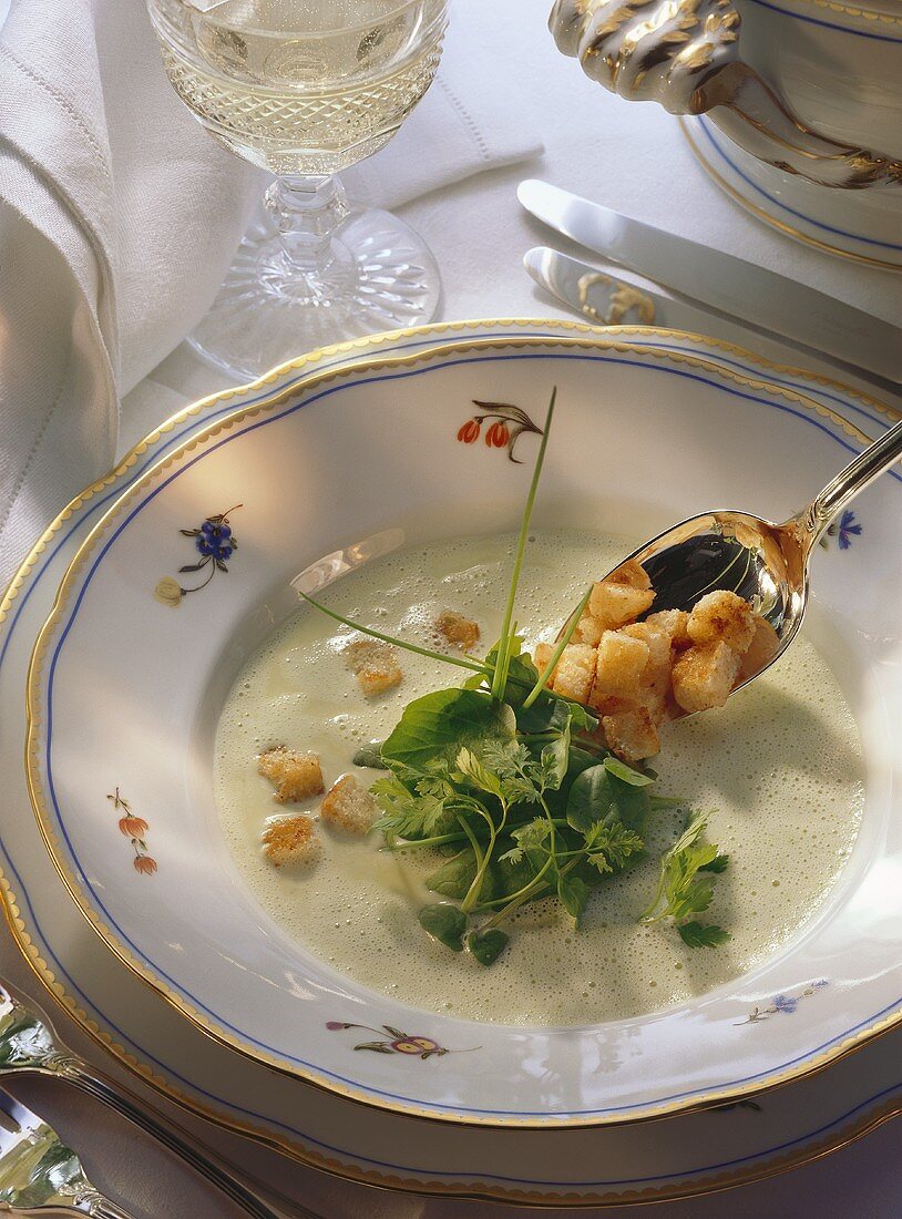 Green cream soup with herb leaves and croutons