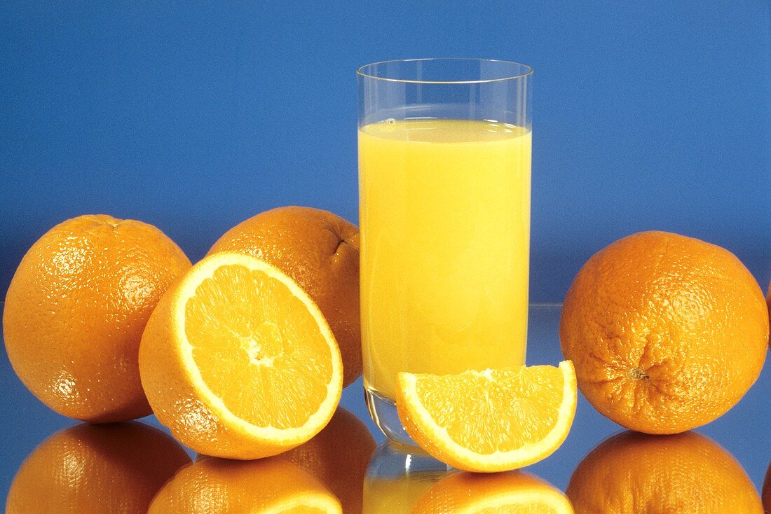 Ein Glas Orangensaft, daneben einige Orangen