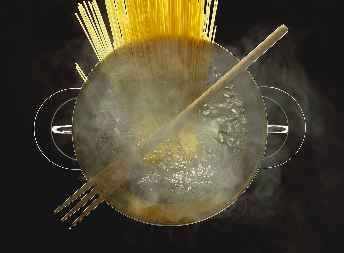 Spaghetti in Topf mit sprudelnd kochendem Wasser & Holzgabel