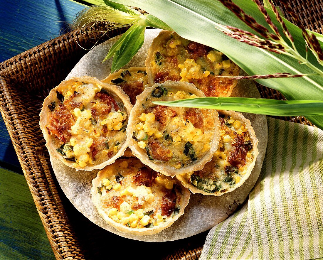 Ham and sweetcorn tartlets on plate with maize plant