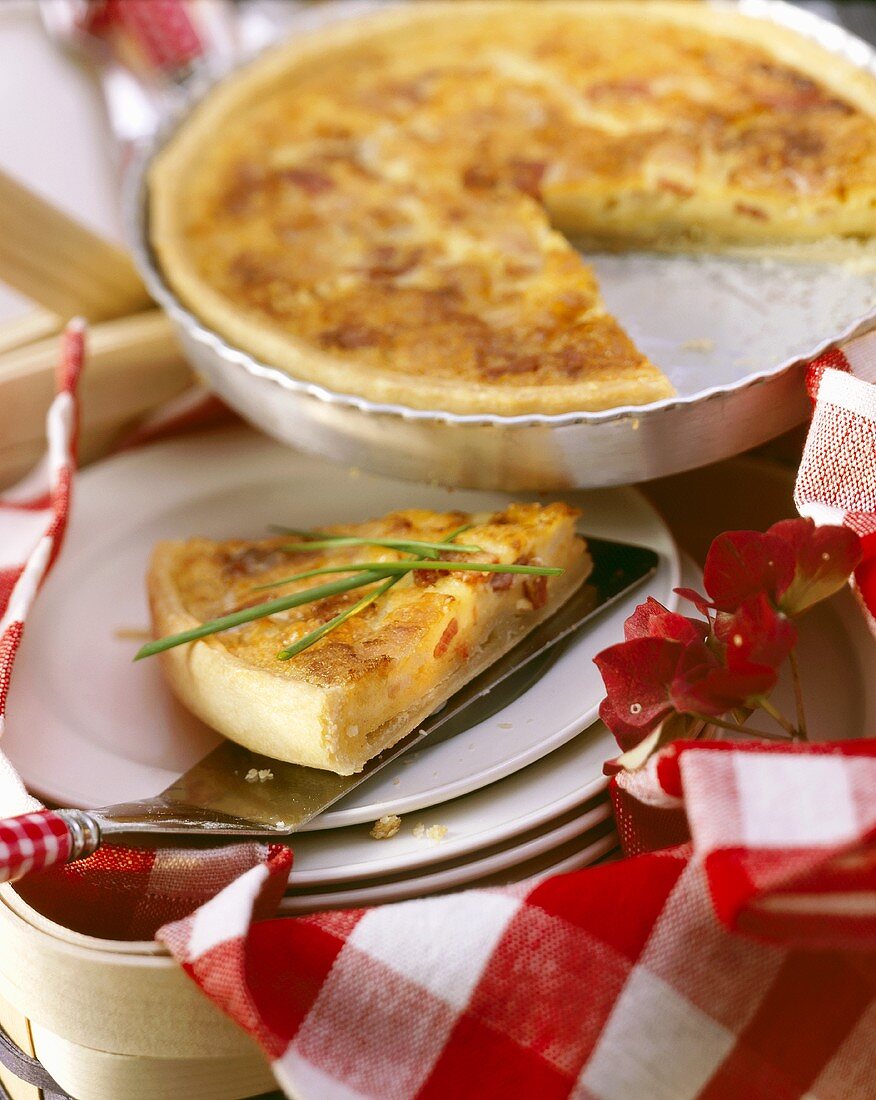 Quiche Lorraine in baking dish and a piece with chives