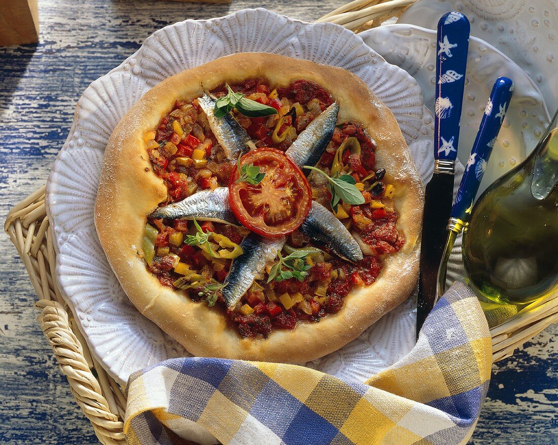 Whole sardine and tomato pizza on plate in wicker tray