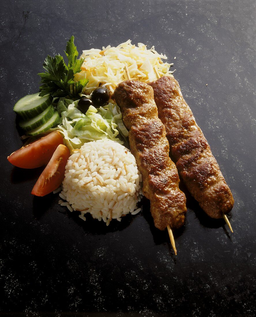 Souvlaki with rice & salad garnish on dark background