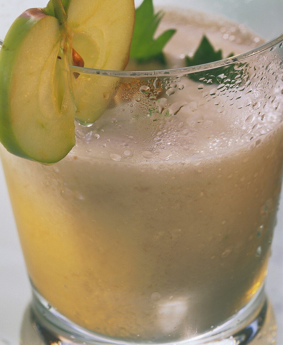 Celery & apple drink with slice of apple on edge of glass