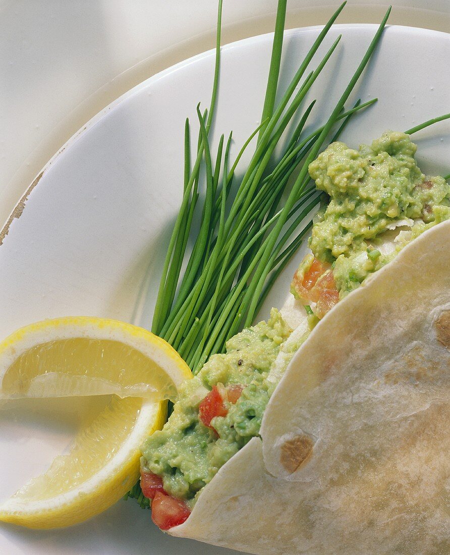 Tortilla with guacamole, chives and lemon wedges