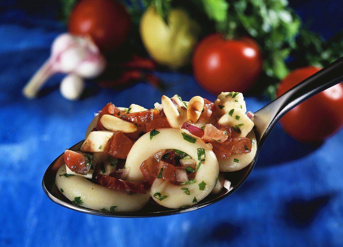 A spoonful of spicy pasta salad with chili and pine nuts