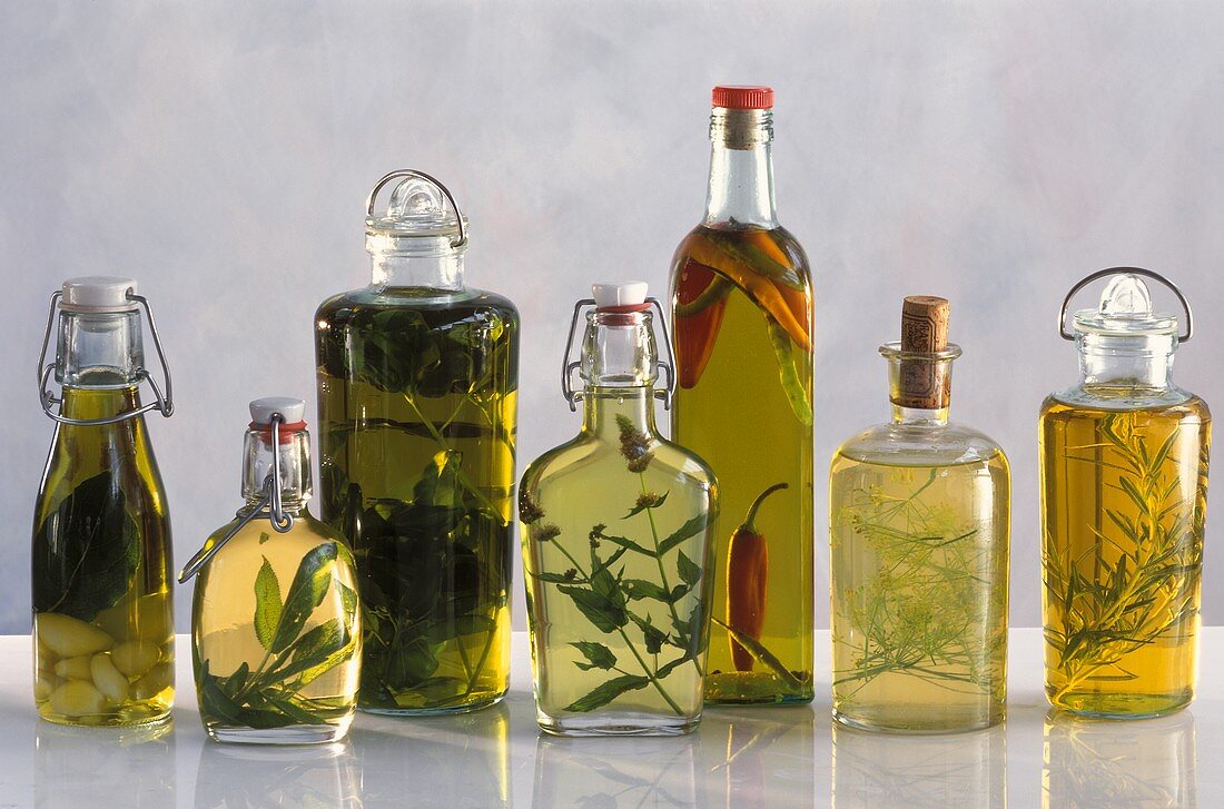 Verschiedene Ölsorten mit Kräutern in Flaschen