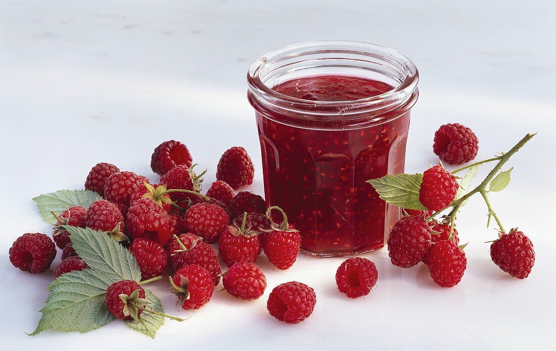 A jar of raspberry jam and raspberries