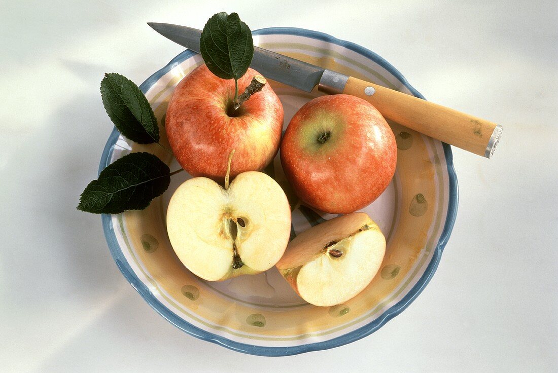 Rote Äpfel auf Teller mit Messer, ein Apfel aufgeschnitten