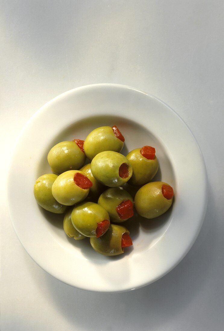 Grüne Oliven, mit Paprika gefüllt, auf weißem Teller