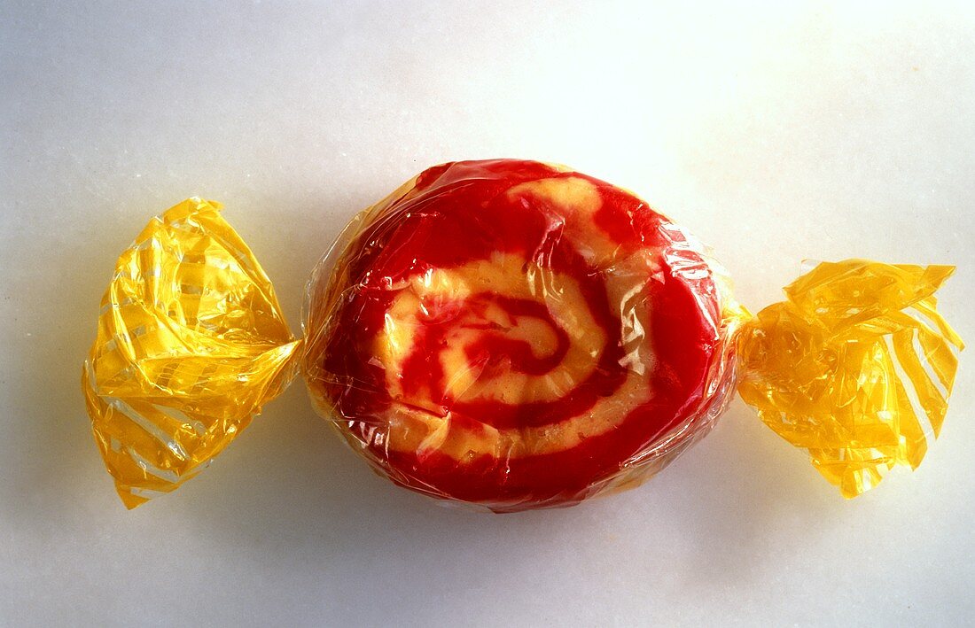 Ein rot-weisses Bonbon in gelber Verpackung