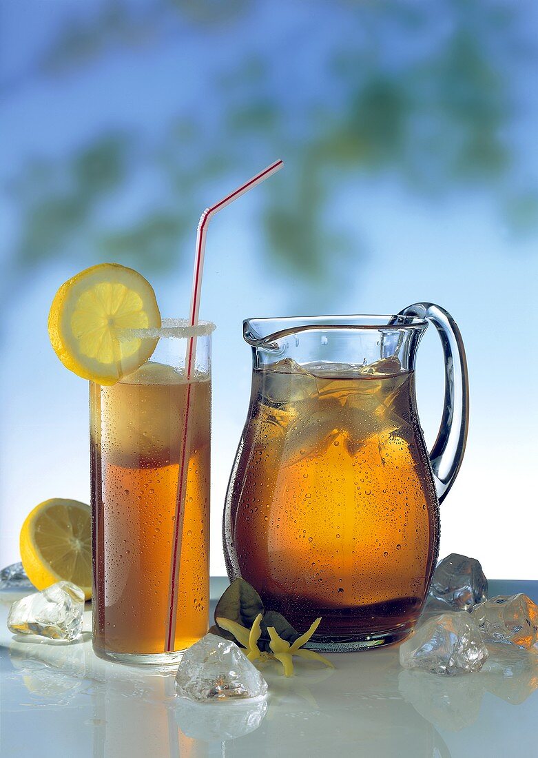Glass of iced tea with ice cream, lemon, straw & jug of tea