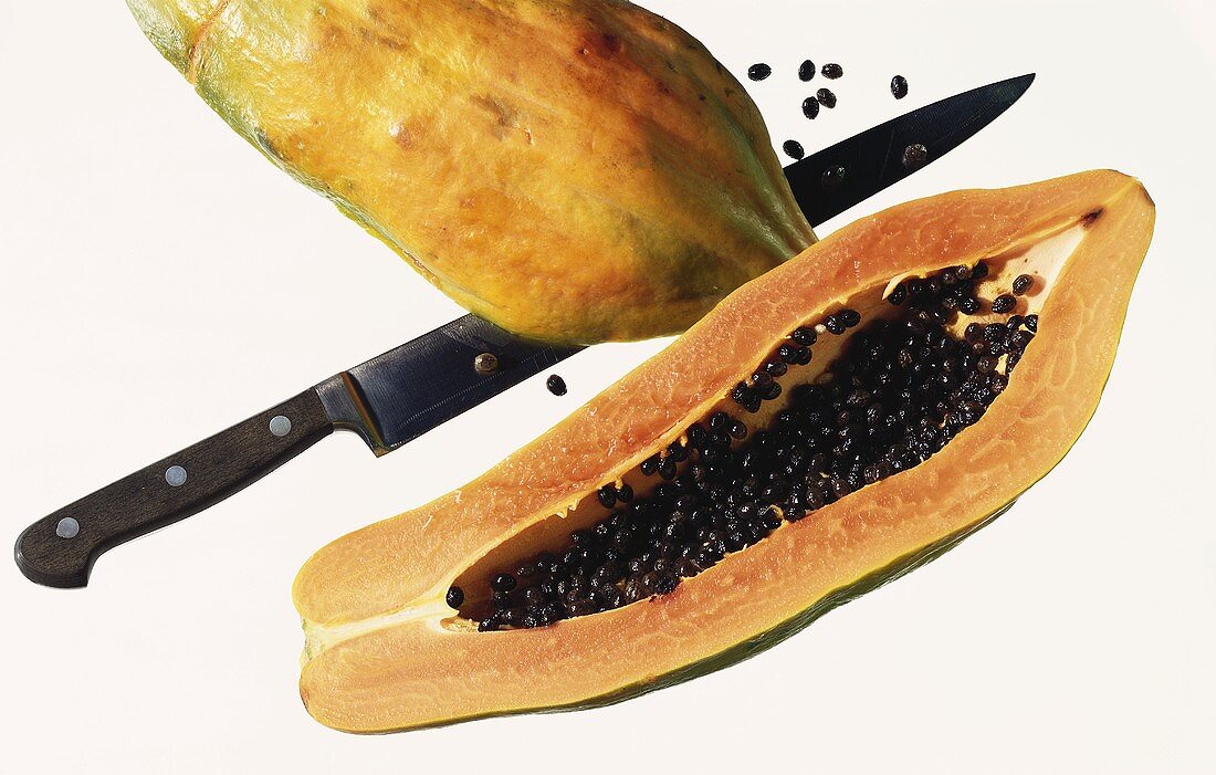 Eine Papaya, in die Hälfte geschnitten mit Kernen & Messer