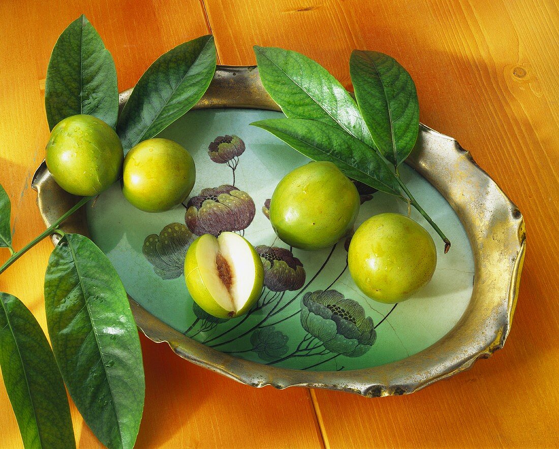 Jujube fruit, one cut open, with leaves on tray
