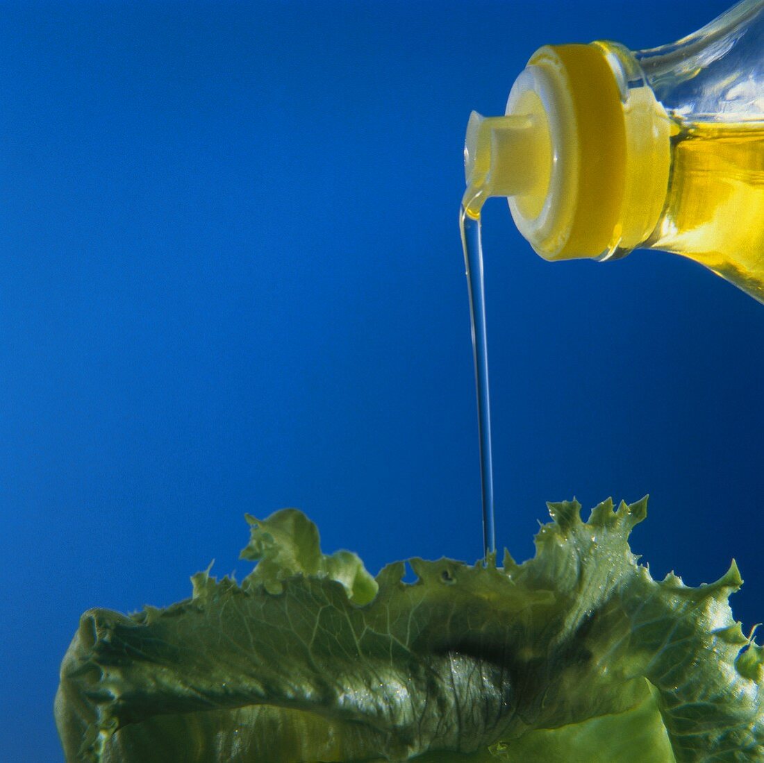 Öl rinnt aus Flasche auf Salatblatt