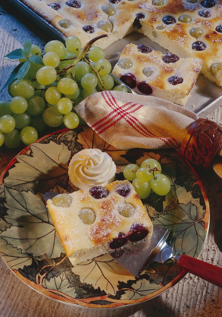 Grape cake with icing sugar and whipped cream