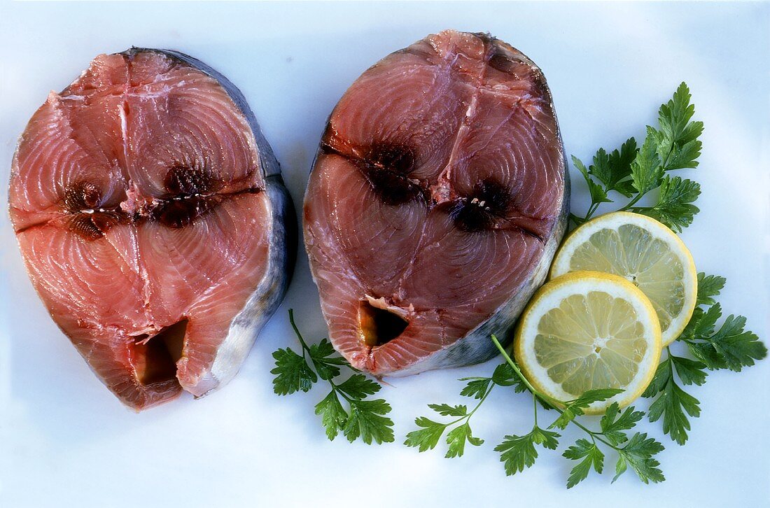 Zwei rohe rote Thunfischsteaks mit Zitronen und Petersilie