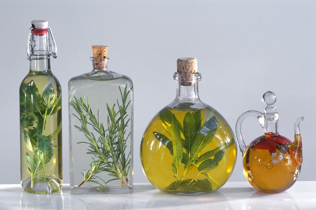 Vier verschiedene Ölflaschen mit Kräutern und Gewürzen