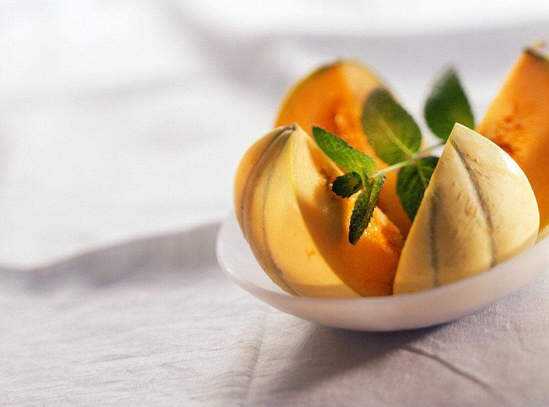 Musk melon, cut in four, with sprig of mint