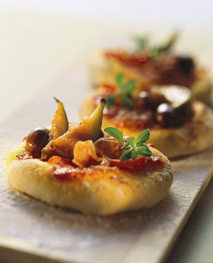 Mini-pizzas with figs, ham, olives & fresh oregano