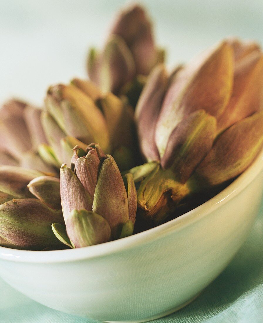 Several artichokes in white bowl