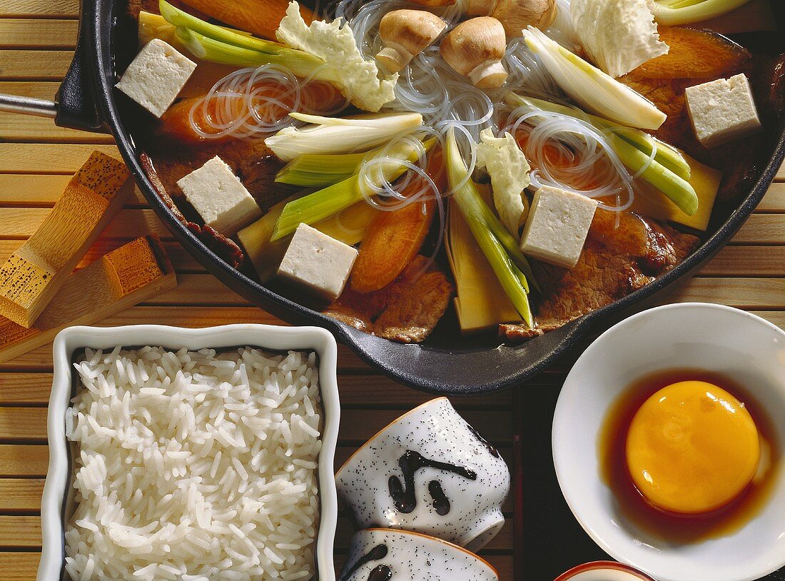 Sukiyaki in pan, egg yolk in soy sauce and rice