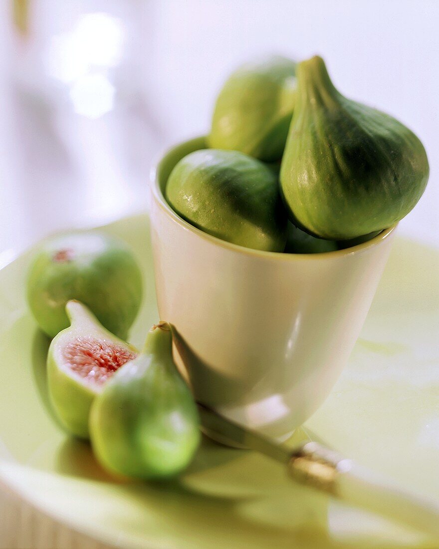 Fresh green figs in a glass and on a plate, one halved