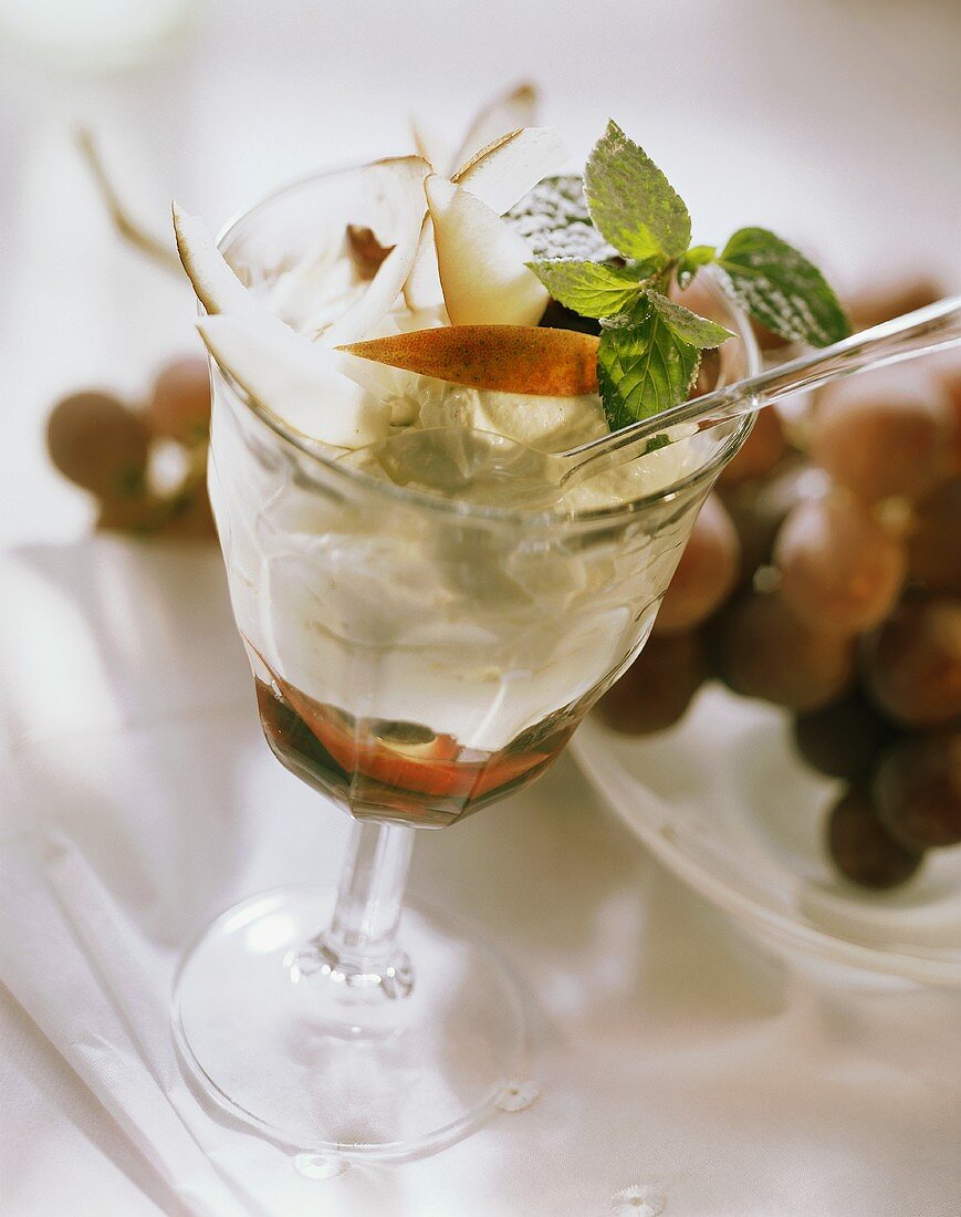 Cream quark with pears, grapes, coconut, mint in stemmed glass