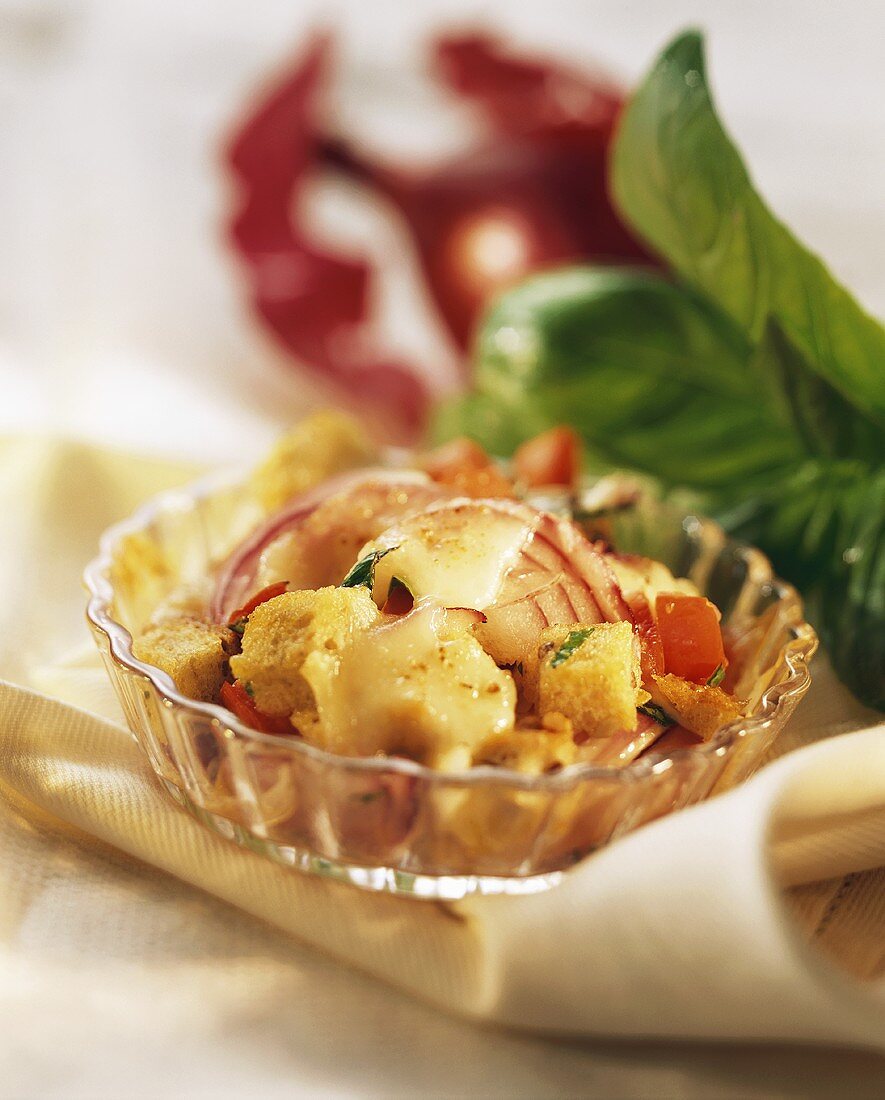 Onion gratin with bread and tomatoes in glass bowl