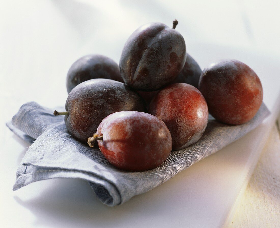 Several plums on blue fabric napkin