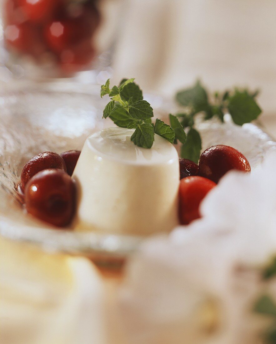 Yoghurt mousse with red wine cherries on glass plate