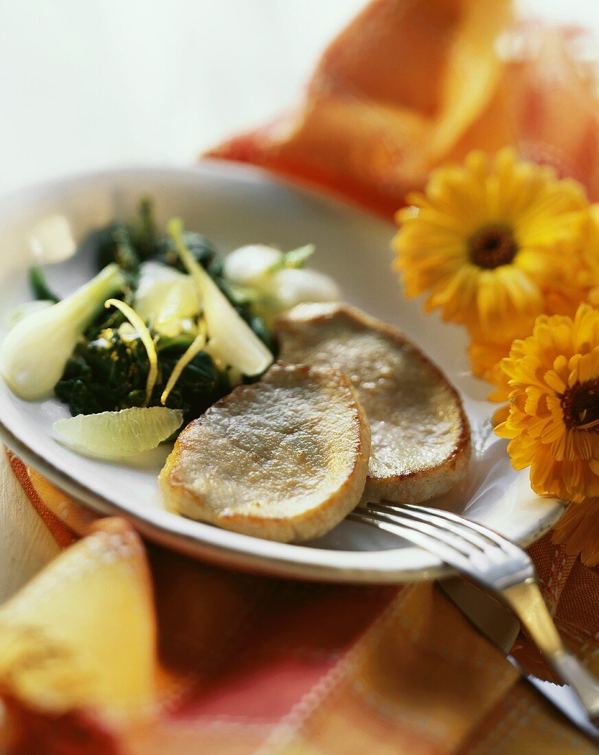 Kalbsschnitzelchen mit Spinat-Zitronen-Gemüse auf Teller
