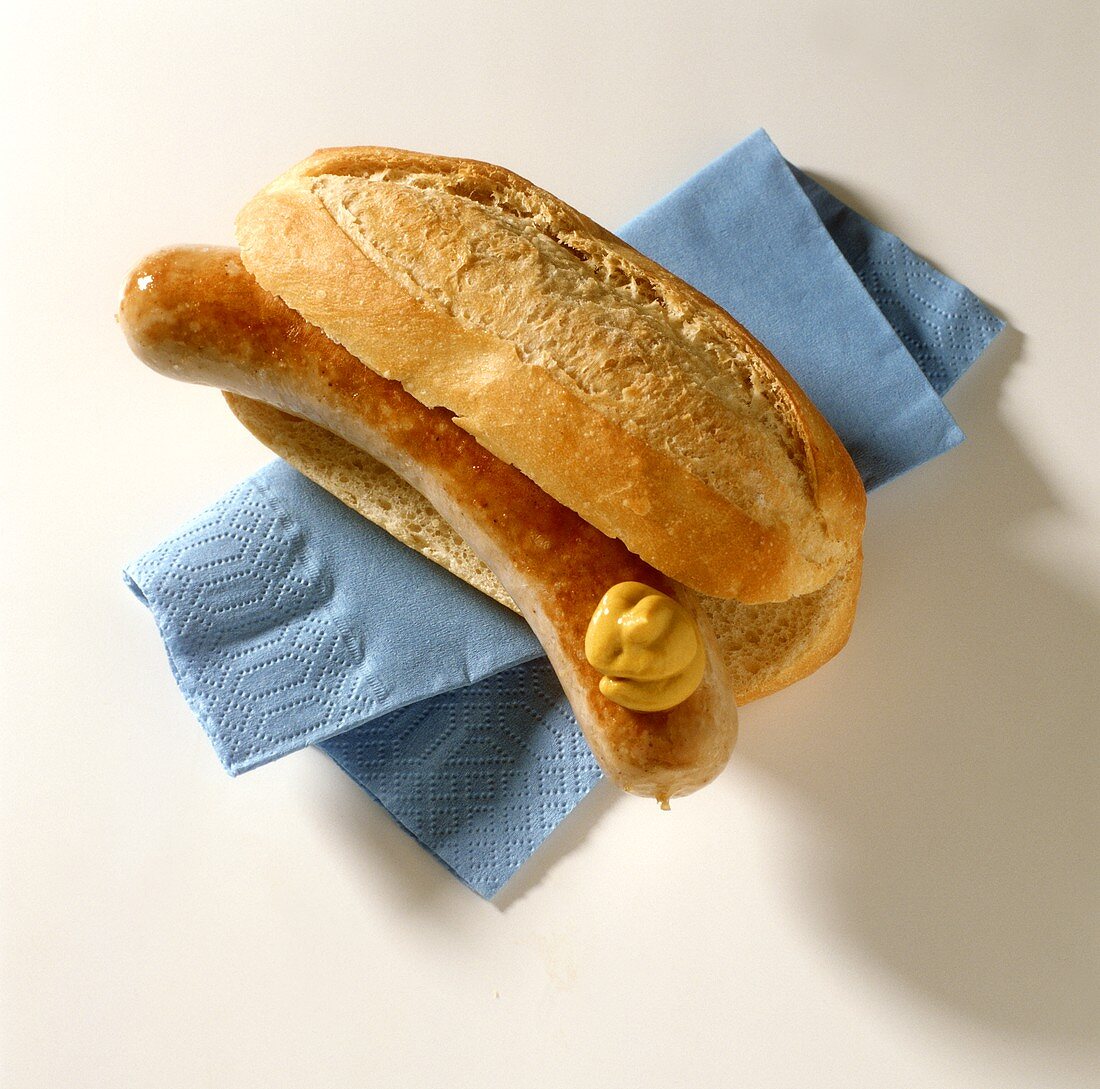 Bratwurst mit Senf in einem Brötchen auf Papierserviette