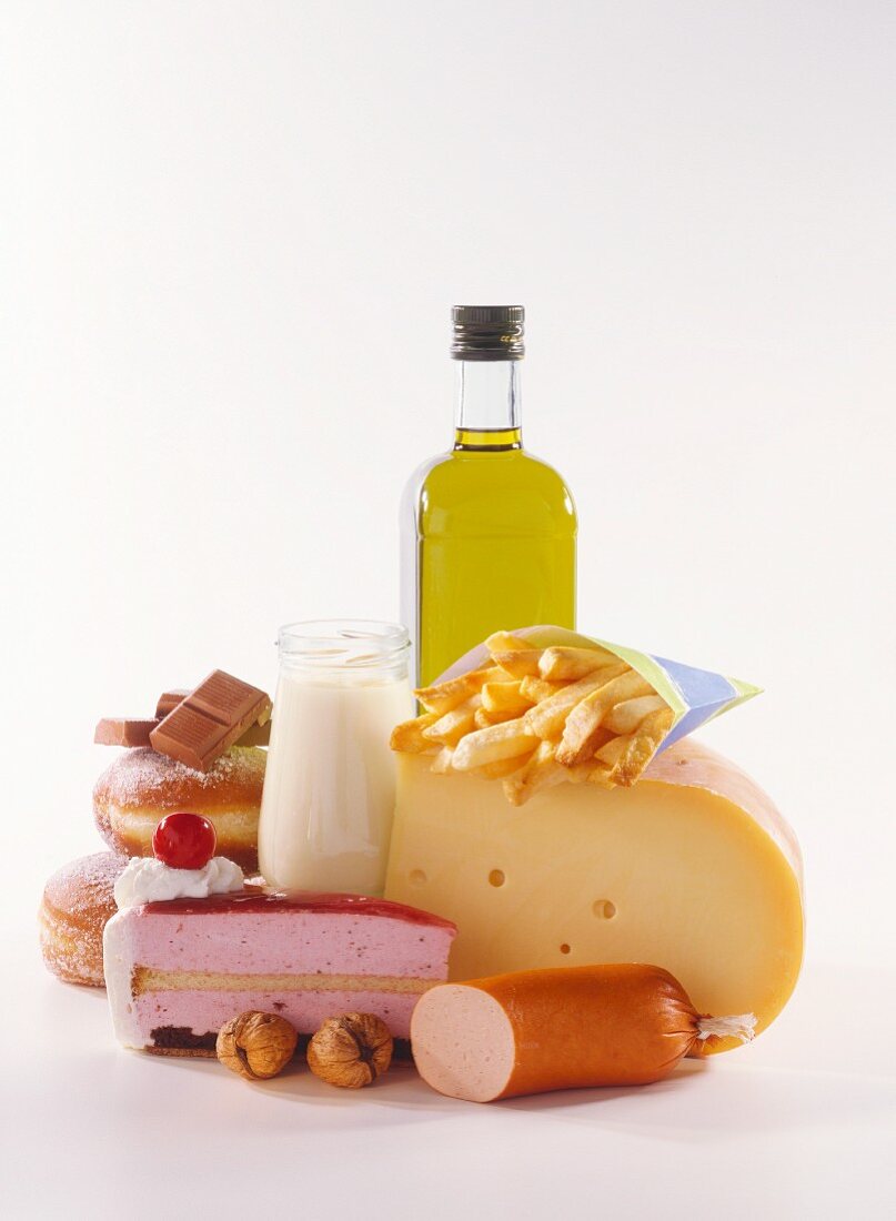 High-calorie still life with cake, cheese, sausage, oil, cream