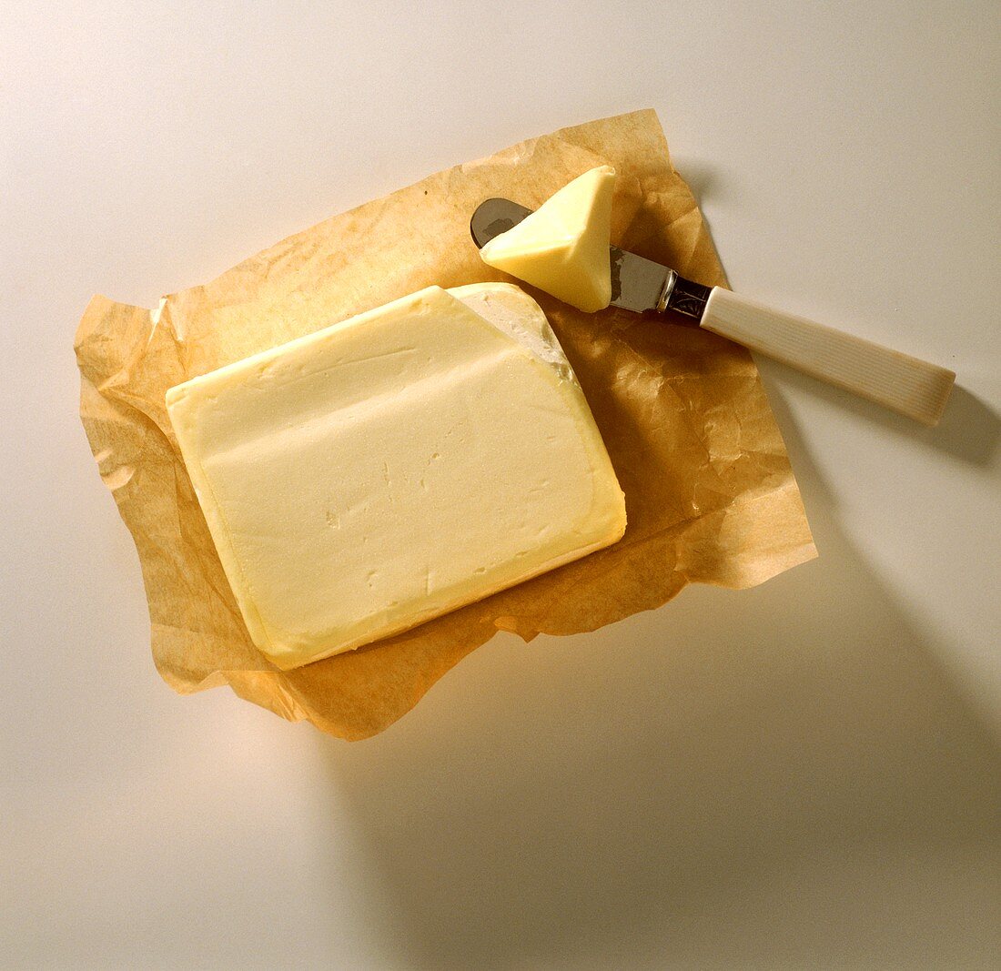 Butter auf Papier und ein Stück auf Buttermesser