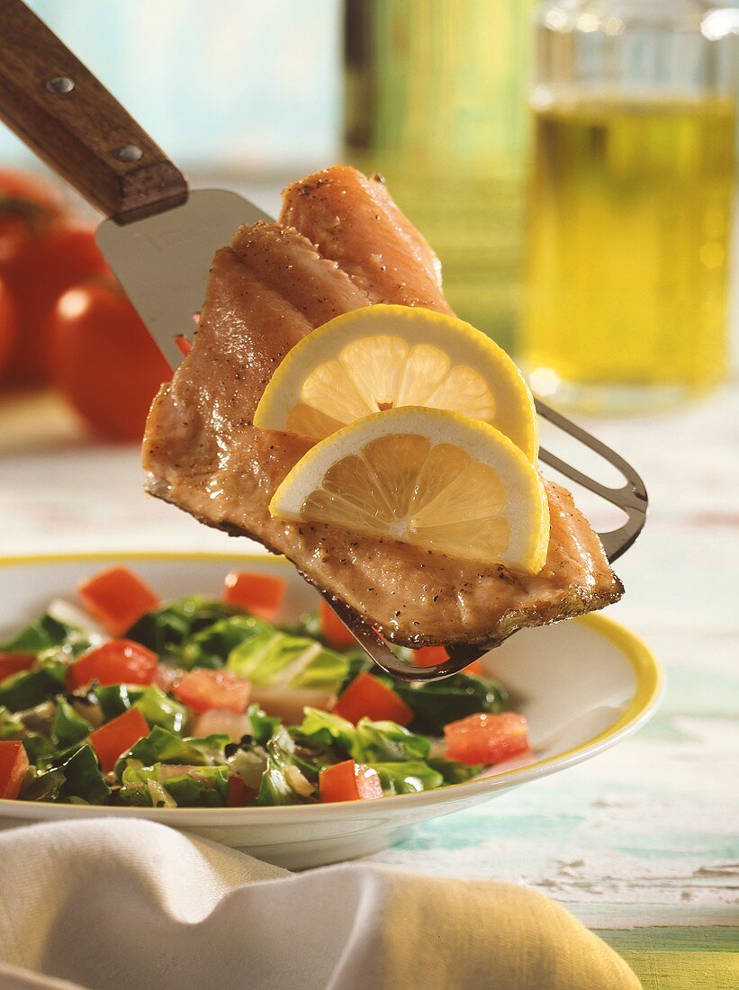 Trout fillet with lemons on server above chard salad