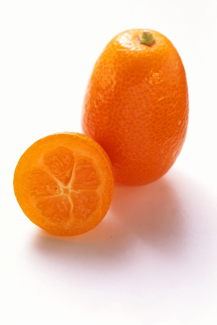 Whole kumquat & halved kumquat on white background