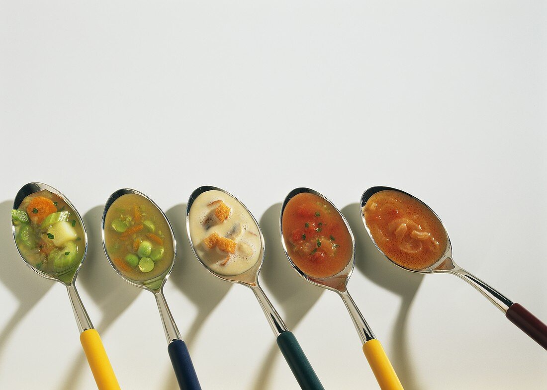 Five different soups on spoons