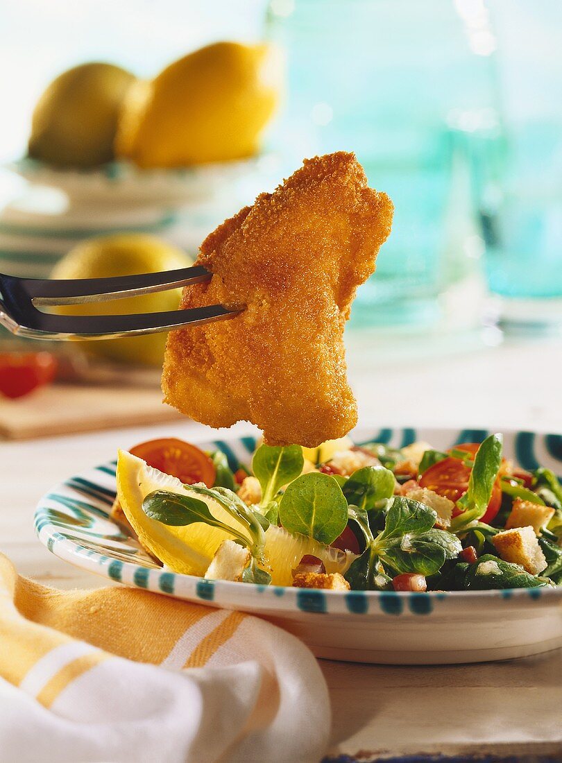 Viennese fried chicken (Backhendl) piece on fork, & corn salad